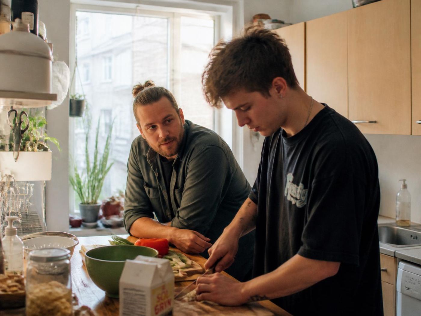 Socialpædagog og ung mand laver mad sammen i et lyst dansk køkken