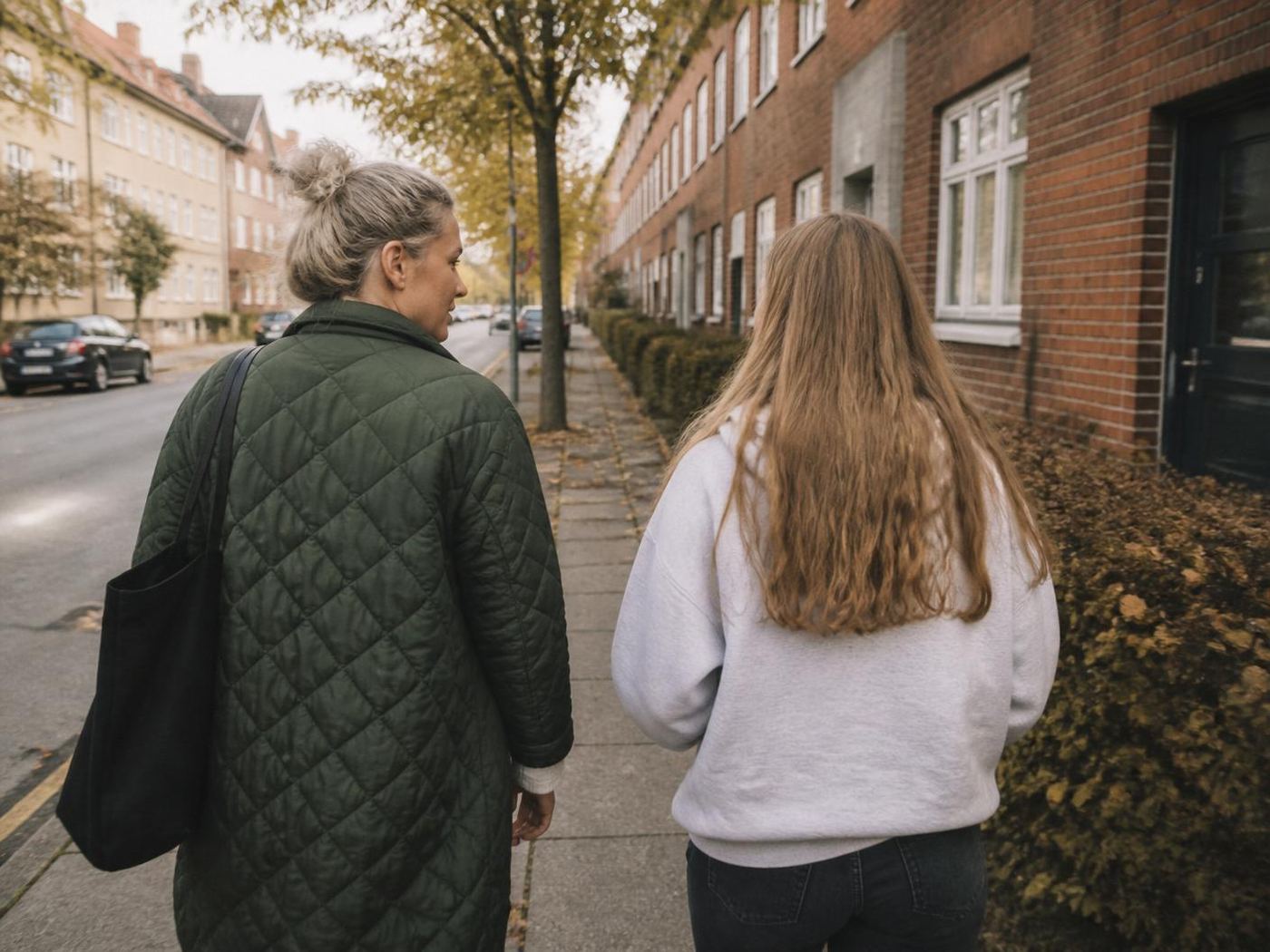 Pædagogisk støtteperson går side om side med ung kvinde på dansk villavej
